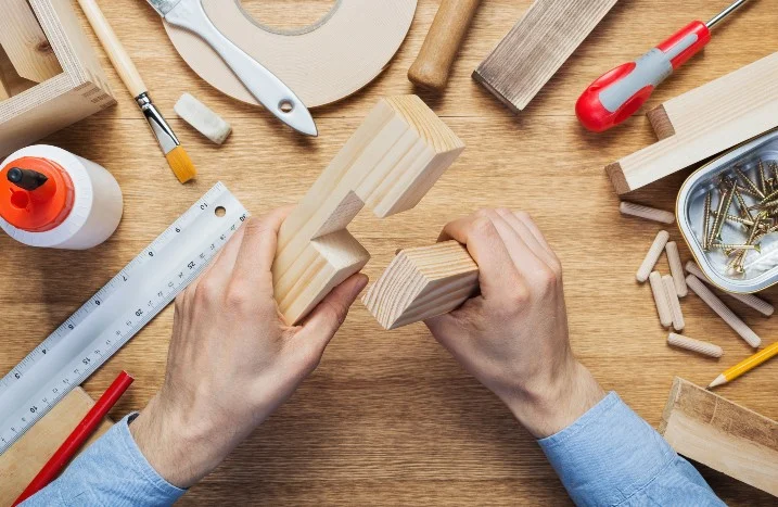 Hände fügen zwei Holzstücke zusammen